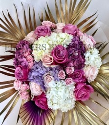 Elegant bouquet with roses, spray roses, and hydrangea, accented with gold leaf and an ombré palm, presented in a signature gift bag.