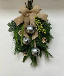 Natural door swag filled with winter foliage, green berries, lime slices, silver bells and a hessian bow. 