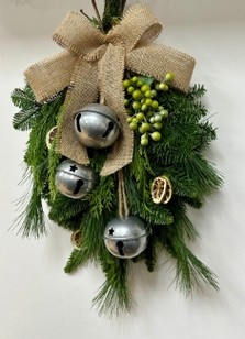 Natural door swag filled with winter foliage, green berries, lime slices, silver bells and a hessian bow. 