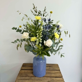Highland Meadow vase arrangement featuring seasonal ivory, yellow and blue-toned florals with natural meadow-style movement, arranged in a blue ceramic vase by Flowers by Bethany.