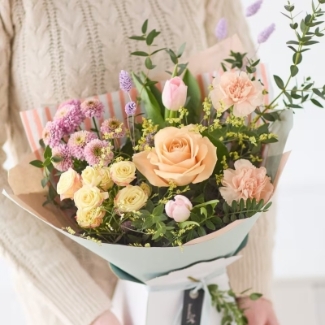 Sweet Apricot hand-tied bouquet featuring seasonal peach, blush and pastel florals with soft texture and natural movement, wrapped in luxury packaging by Flowers by Bethany.