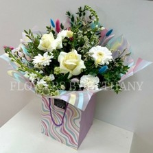 All white bouquet with a whimsical twist, pastel bunny tails dispersed through the bouquet. Wrapped in a wavy print bag and cellophane hand tied in water. 