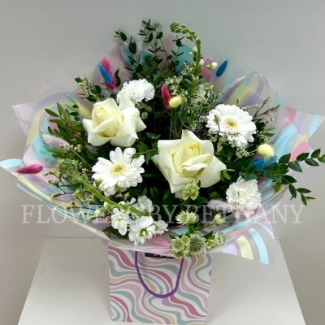All white bouquet with a whimsical twist, pastel bunny tails dispersed through the bouquet. Wrapped in a wavy print bag and cellophane hand tied in water. 