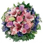 Pink and purple funeral posy with lilies, roses, seasonal flowers, mixed foliage, and looped grass or wire for a modern touch.