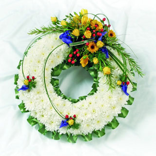 White chrysanthemum funeral wreath with bold yellow, green, and red accents, creating a vibrant tribute.