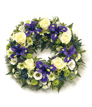 Loose funeral wreath with purple, white, and lime green seasonal flowers, symbolising remembrance and love.