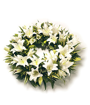 Classic round funeral wreath with oriental lilies and complementary mixed foliage, offering an elegant and dramatic tribute.