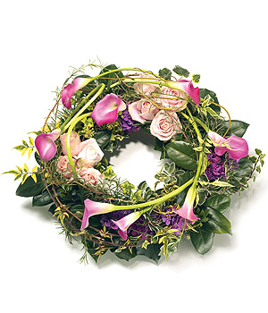 Loose funeral wreath in pink and green shades, featuring mixed luxury florals and complemented with foliage.